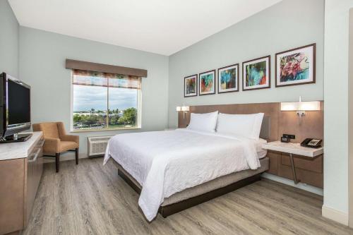 棕榈滩花园棕榈滩花园希尔顿花园酒店的一间卧室配有一张床、一张书桌和一台电视