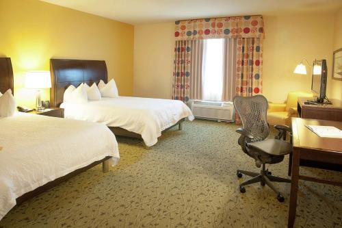 彭萨科拉彭萨科拉机场/医疗中心希尔顿花园酒店的酒店客房 - 带两张床、一张桌子和一把椅子