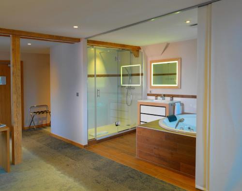 朗巴克奥伯格切瓦尔布兰科温泉酒店的带浴缸和玻璃淋浴间的浴室。