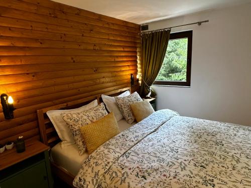 Muntele CacoveiMountain Chalet - Cabana la Muntele Baisorii的一间卧室设有木墙和一张带枕头的床。