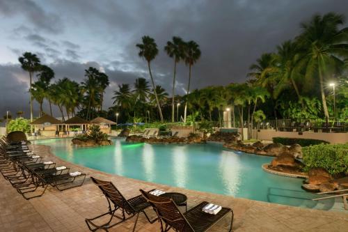 圣胡安圣胡安希尔顿合博套房酒店 - 酒店及赌场的一个带椅子和棕榈树的度假村游泳池