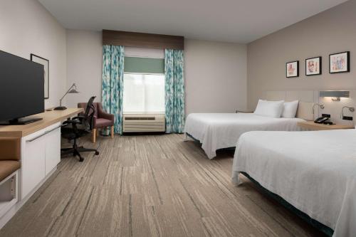 诺克斯维尔西诺克斯维尔/雪松崖希尔顿花园酒店的酒店客房设有两张床、一张桌子和一台电视。