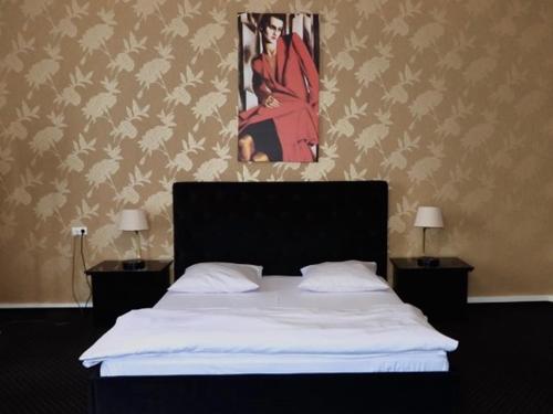 什切青Matejki 8的卧室配有一张床,墙上挂有绘画作品