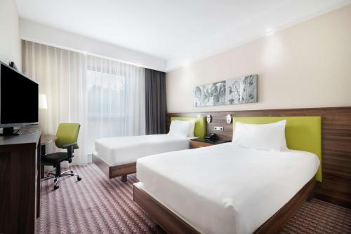 克拉科夫克拉科夫希尔顿汉普顿酒店的酒店客房设有两张床、一张桌子和一台电视。