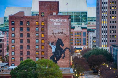 休斯顿休斯敦山姆希尔顿Curio Collection酒店的一座建筑物旁边骑马的人的壁画