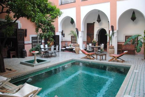 马拉喀什里亚德巴洛克旅馆的庭院内的游泳池,配有桌椅