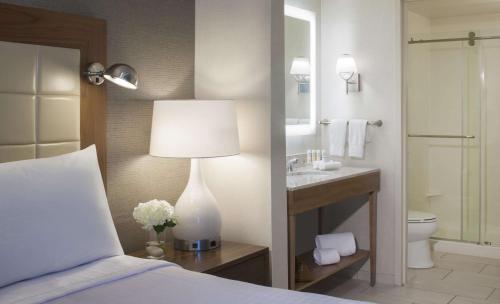 迈阿密迈阿密海豚购物中心希尔顿惠庭套房酒店的一间卧室配有一张床,浴室设有水槽