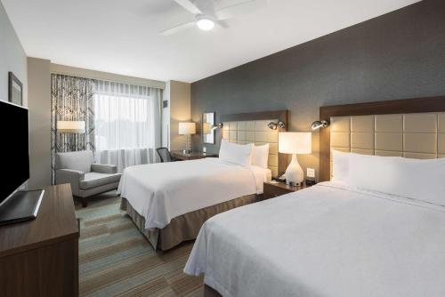 迈阿密迈阿密海豚购物中心希尔顿惠庭套房酒店的酒店客房,配有两张床和椅子