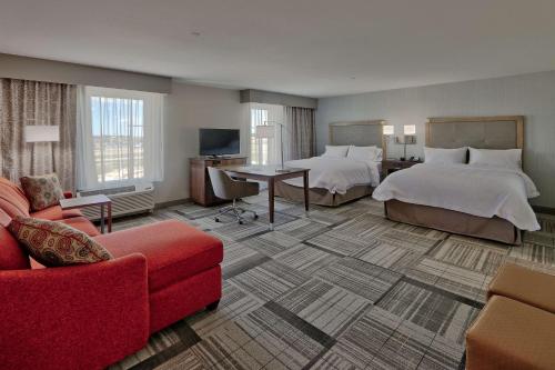 阿蒂西亚阿蒂西亚汉普顿套房酒店的酒店客房带两张床和一张红色沙发