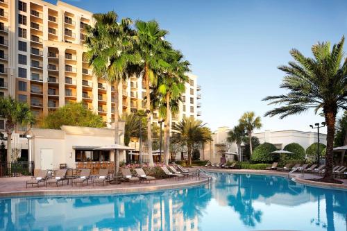 奥兰多Hilton Grand Vacations Club Las Palmeras Orlando的酒店前方的游泳池设有椅子和棕榈树