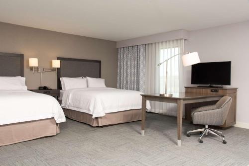 密歇根城密歇根市汉普顿酒店的酒店客房设有两张床、一张桌子和一台电视。