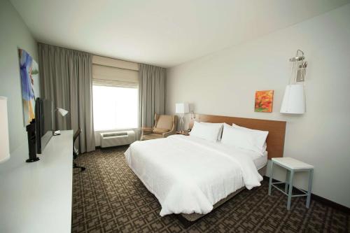 圣安东尼奥圣安东尼奥-活橡树会议中心希尔顿花园酒店的酒店客房,配有白色的床和椅子