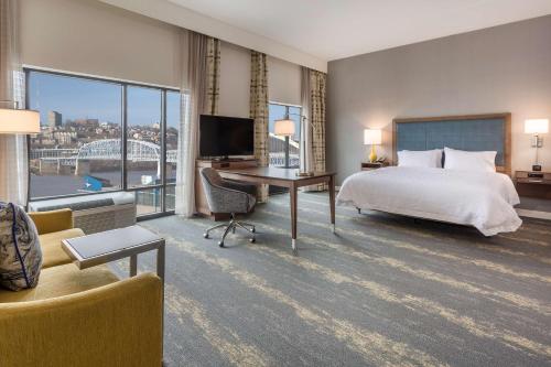 纽波特肯塔基辛辛那提新港汉普顿套房汽车旅馆的酒店客房配有一张床和一张书桌及一台电视