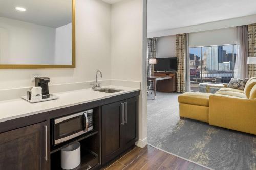 纽波特肯塔基辛辛那提新港汉普顿套房汽车旅馆的一间带水槽的厨房和一间带沙发的客厅