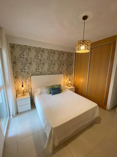 维拉Lagunas Home, bajo con terraza al lado de la playa的卧室配有一张白色大床和吊灯。