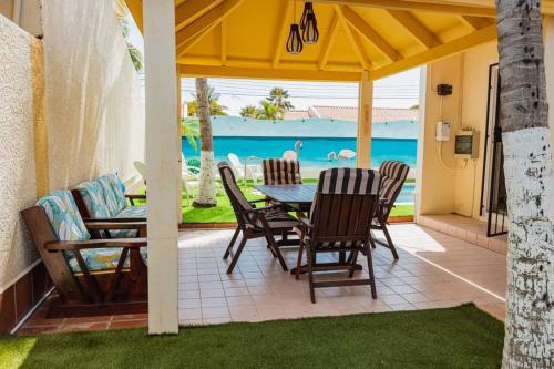 SavanetaBlue Sky Residence Aruba的一个带桌椅的庭院和大海