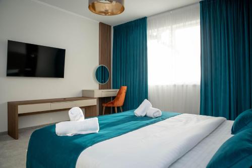 布勒伊拉Unique Garden Hotel的一间卧室配有一张带蓝色窗帘的床和电视。