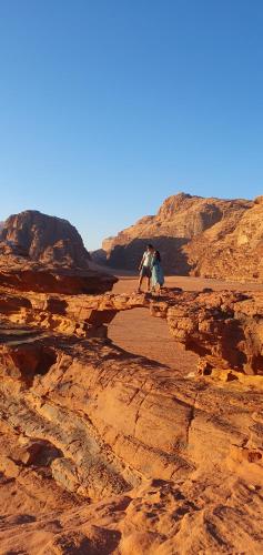 亚喀巴Bedouin experiences的两个人站在沙漠的岩石上