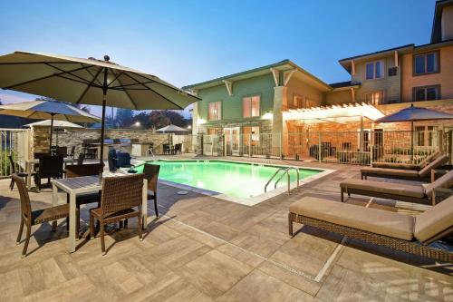 普莱森特希尔Homewood Suites by Hilton Pleasant Hill Concord的一个带桌椅和遮阳伞的游泳池