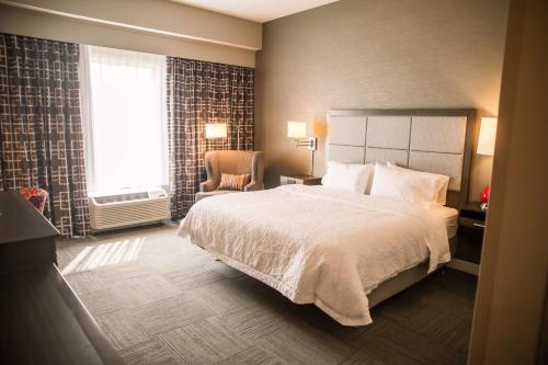 庞蒂亚克庞蒂亚克汉普顿酒店的卧室配有床、椅子和窗户。