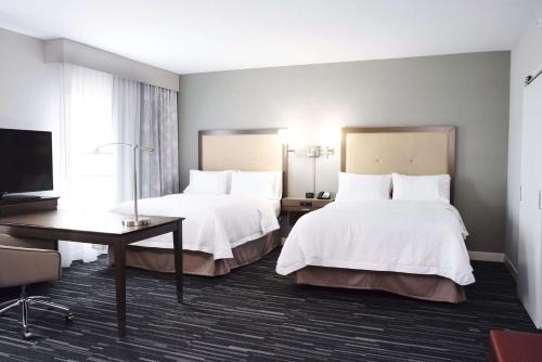 Urbandale得梅因/厄班代尔汉普顿酒店的酒店客房设有两张床、一张桌子和一台电视。