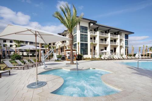 圣奥古斯丁海滩Embassy Suites St Augustine Beach Oceanfront Resort的一个带椅子和遮阳伞的游泳池以及酒店