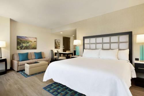 圣安东尼奥Embassy Suites By Hilton San Antonio Landmark的一间带白色大床的卧室和一间客厅