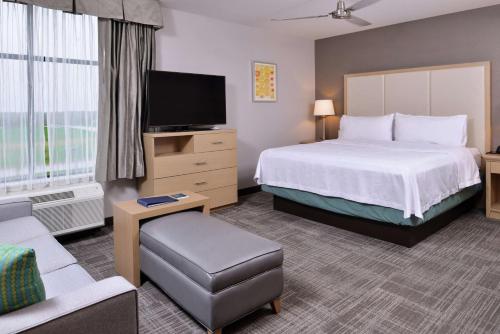 德梅因Homewood Suites Des Moines Airport的配有一张床和一台平面电视的酒店客房