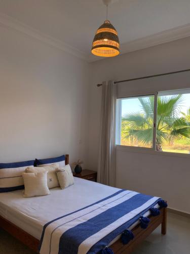 艾西拉Asilah marina golf的一间卧室设有一张床,窗户拥有棕榈树