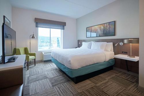 康宁Hilton Garden Inn Corning Downtown的酒店客房配有一张床、一张书桌和一台电视。