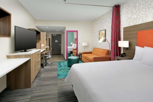 莱克兰Home2 Suites By Hilton Lakeland的配有一张床和一台平面电视的酒店客房
