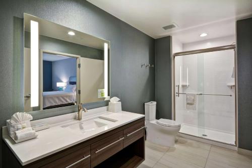 普莱诺Home2 Suites Plano Legacy West的一间带水槽、卫生间和镜子的浴室