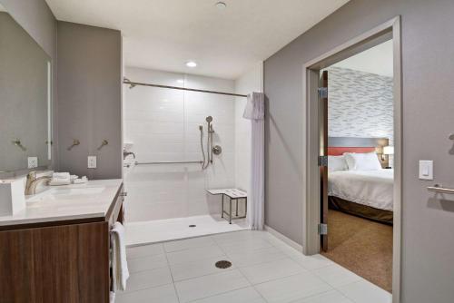 贝德福德Home2 Suites By Hilton Bedford Dfw West的一间带水槽和淋浴的浴室以及一张床