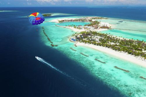 南马累环礁SAii Lagoon Maldives, Curio Collection By Hilton的海岛,有降落伞飞越海洋