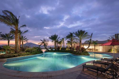 惠东惠东富力希尔顿逸林度假酒店的度假村内棕榈树游泳池