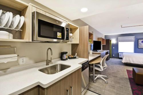 华纳罗宾斯Home2 Suites By Hilton Warner Robins的带水槽的厨房和1间带床的房间