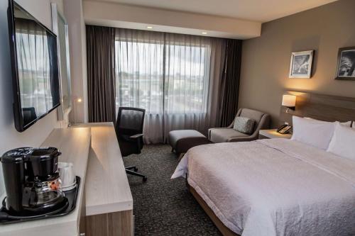 普埃布拉Hampton Inn & Suites By Hilton Puebla的配有一张床和一把椅子的酒店客房