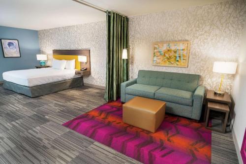 圣安东尼奥Home2 Suites By Hilton San Antonio At The Rim, Tx的一张床铺和一张沙发的酒店客房的 ⁇ 染