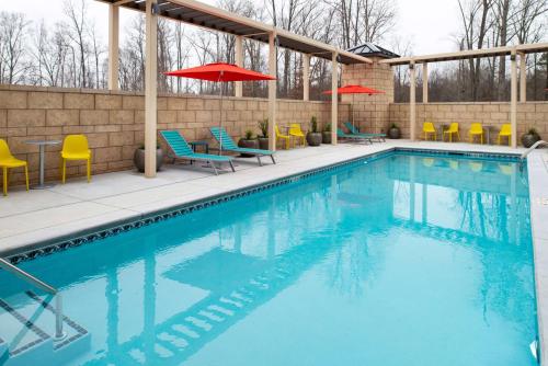 穆尔斯维尔Home2 Suites By Hilton Charlotte Mooresville, Nc的一座大楼内的游泳池,配有椅子和遮阳伞