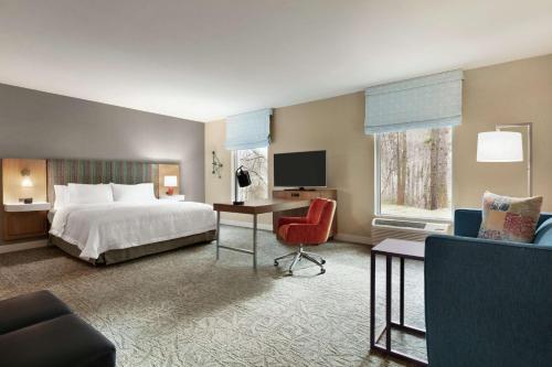 约翰斯克里克Hampton Inn And Suites By Hilton Johns Creek的酒店客房配有一张床、一张桌子和一把椅子。