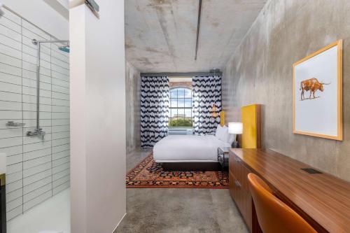 欧文NYLO Las Colinas Hotel, Tapestry Collection by Hilton的客房内的1间带1张床和淋浴的浴室