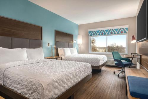 格林维尔Tru By Hilton Greenville Woodruff Road, SC的酒店客房带两张床、椅子和窗户