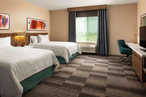 萨克拉门托Hilton Garden Inn Sacramento Airport Natomas的酒店客房设有两张床和窗户。