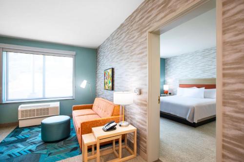 卡尔斯巴德Home2 Suites By Hilton Carlsbad, Ca的配有一张床和一把椅子的酒店客房