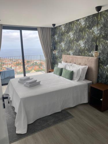 丰沙尔Atlântico Azul的卧室设有一张大白色的床和大窗户