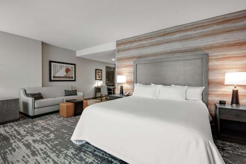 琼斯伯勒Embassy Suites Jonesboro - Arkansas State的酒店客房设有一张大床和一张沙发。