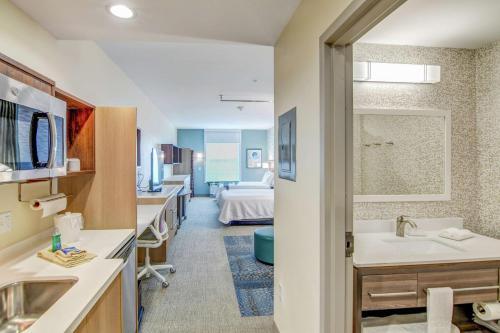 弗利Home2 Suites By Hilton Foley的一间带水槽的浴室和一张位于客房内的床
