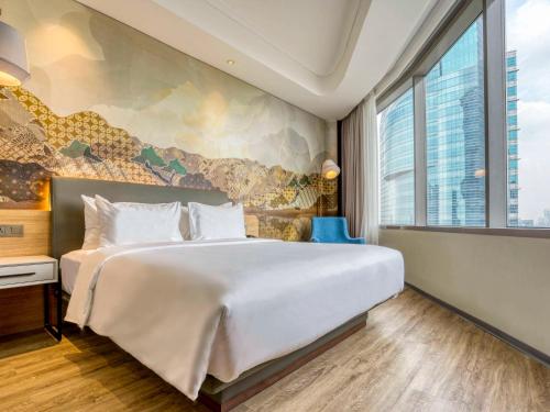 雅加达Mercure Jakarta Gatot Subroto的一间卧室设有一张大床和一个大窗户