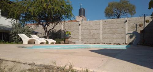 温基约Cabaña Raices的一个带白色椅子和墙壁的游泳池