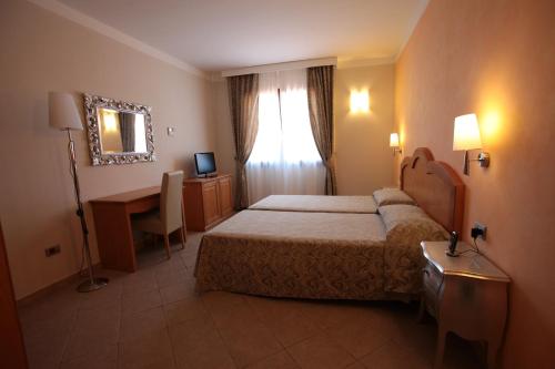 阿尔巴塔克斯Hotel La Perla的一间卧室配有一张床、一张书桌和一面镜子